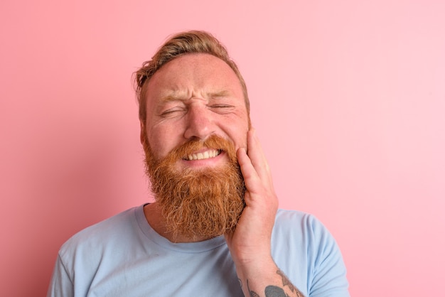 Hombre feliz con camiseta azul claro tiene dolor en los dientes