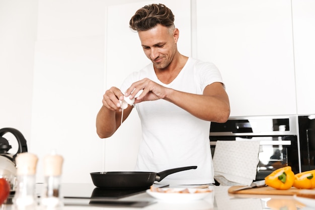 Hombre feliz cocinando huevos para el desayuno