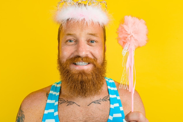 Hombre feliz con corona de princesa y varita mágica actúa como un hada