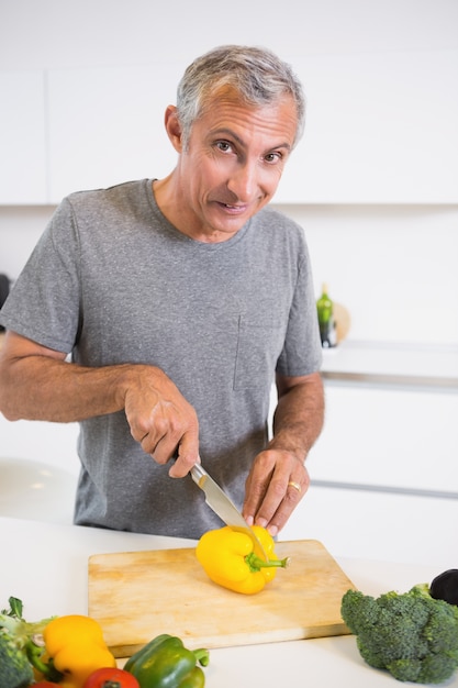 Hombre feliz cortando un pimiento amarillo