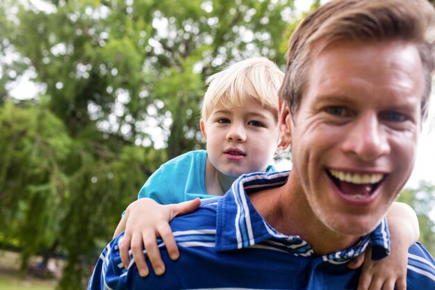 Hombre feliz dando caballito a su hijo