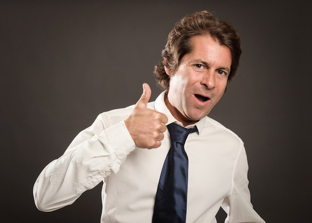 Hombre feliz dando un signo de pulgares arriba en gris