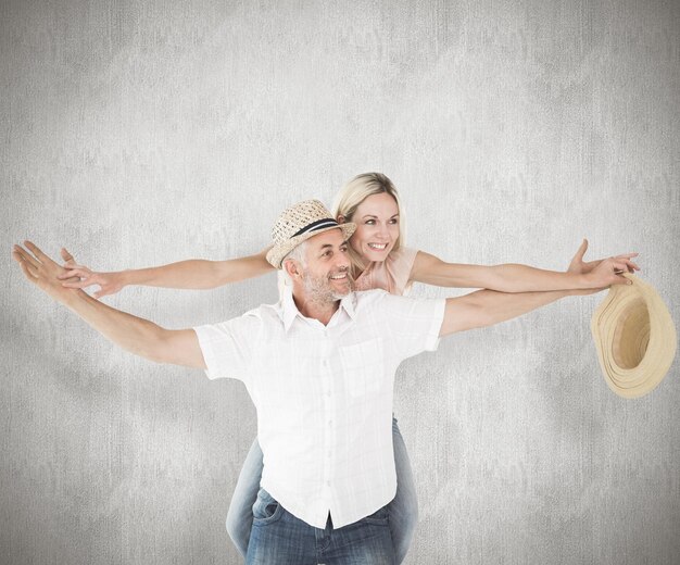 Foto hombre feliz dando a su pareja un piggy back contra la superficie erosionada