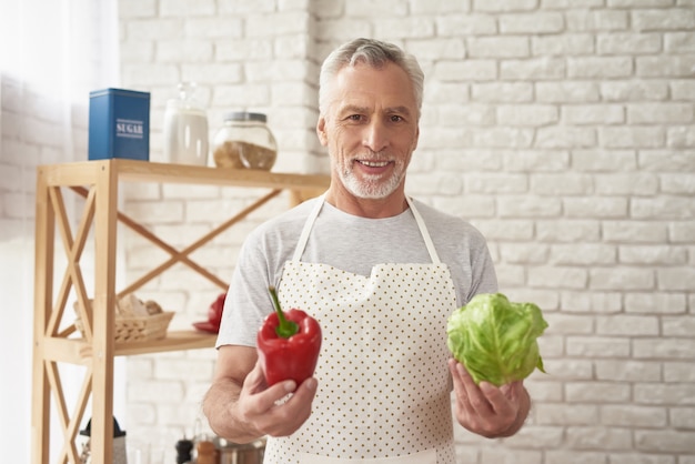 Hombre feliz en delantal con verduras en las manos.