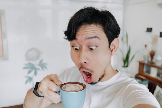 Hombre feliz disfruta de su café y selfie a sí mismo con su taza de café