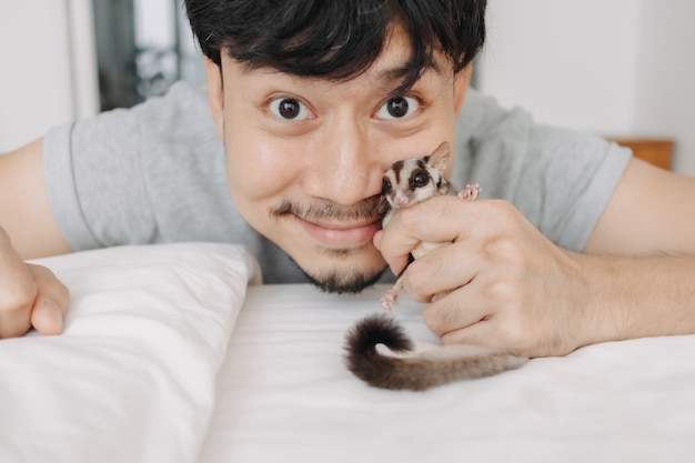 Hombre feliz está jugando con su planeador del azúcar mascota mientras se queda en casa