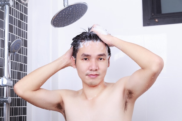 hombre feliz está tomando una ducha de lluvia y lavando el cabello