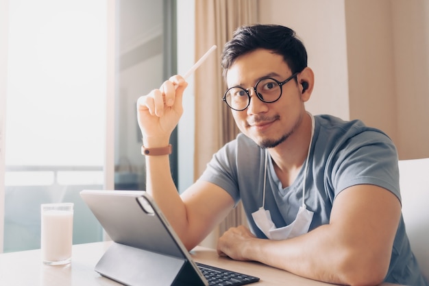 Hombre feliz está trabajando en su tableta en concepto de trabajo desde casa