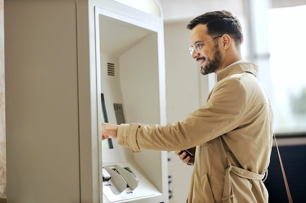 Un hombre feliz está usando cajero automático