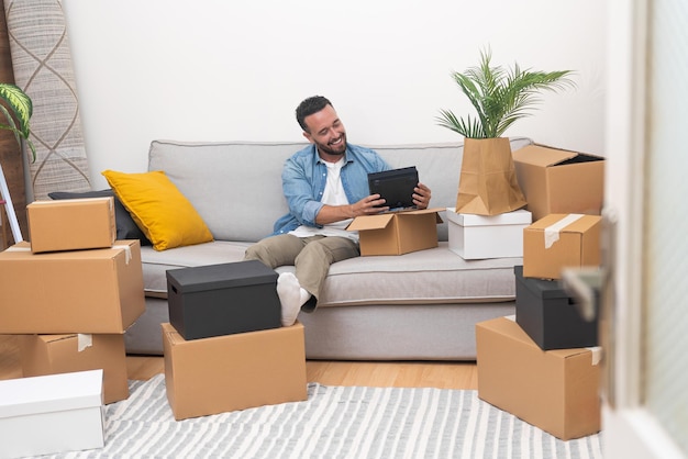 Hombre feliz con expresión de deleite se sienta en un sofá acogedor