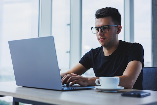 Hombre feliz con gafas ópticas para la corrección de la visión en busca de información divertida en las redes sociales mediante conexión inalámbrica en el concepto de tecnología netbook