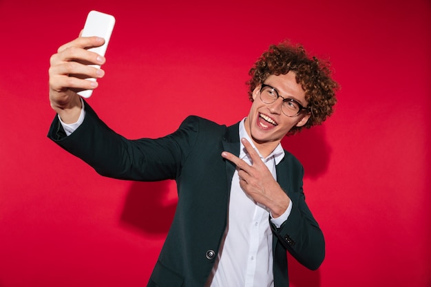 Hombre feliz en gafas tomando selfie y mostrando gesto de paz