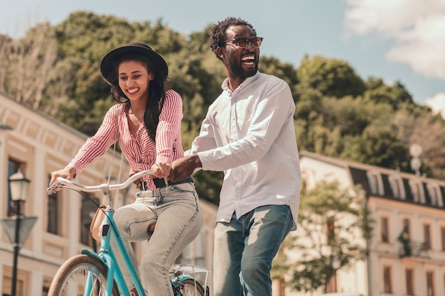 Hombre feliz girando y sonriendo mientras mujer sonriente en bicicleta