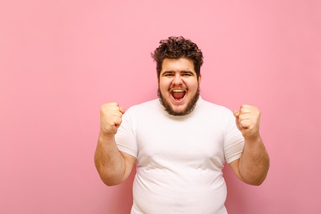 Un hombre feliz, gordo y alegre con barba levantó las manos de alegría Copiar espacio