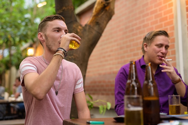 Hombre feliz hablando y bebiendo cerveza con amigos