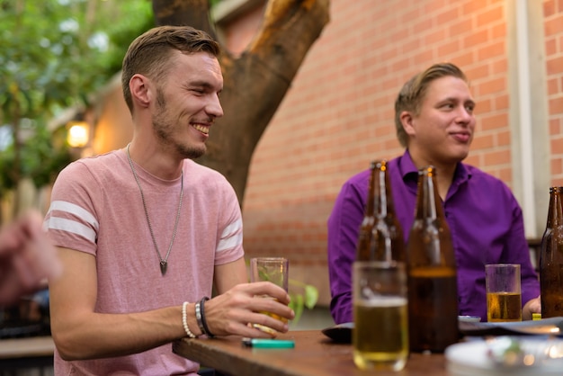 Hombre feliz hablando y bebiendo cerveza con amigos