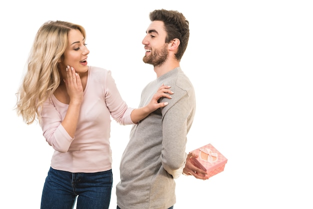 El hombre feliz hace una sorpresa con una caja de regalo a una mujer sobre un fondo blanco.