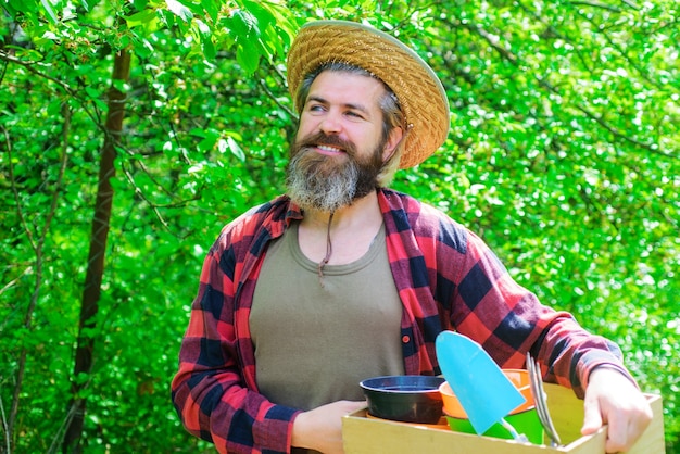 Hombre feliz en el jardín de primavera. Jardinero en granja ecológica con siembra de herramientas de jardinería.