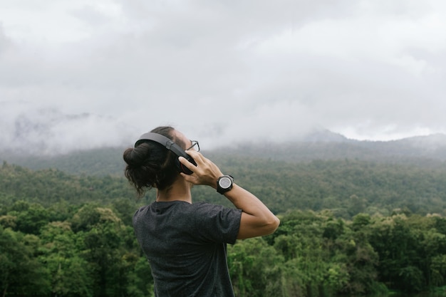 Hombre feliz joven, música que escucha del hombre a través de los auriculares en el teléfono móvil en parque