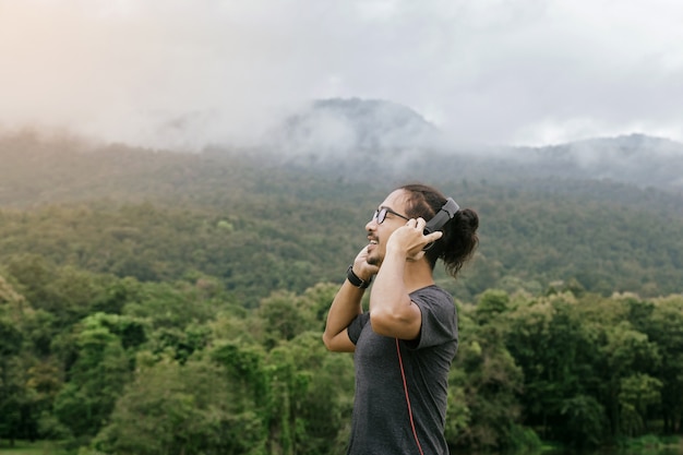 Hombre feliz joven, música que escucha del hombre a través de los auriculares en el teléfono móvil en parque