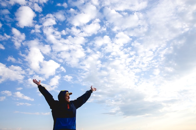 Foto hombre feliz levantó los brazos abiertos viajando cielo azul y nubes estilo de vida saludable libertad de aventura