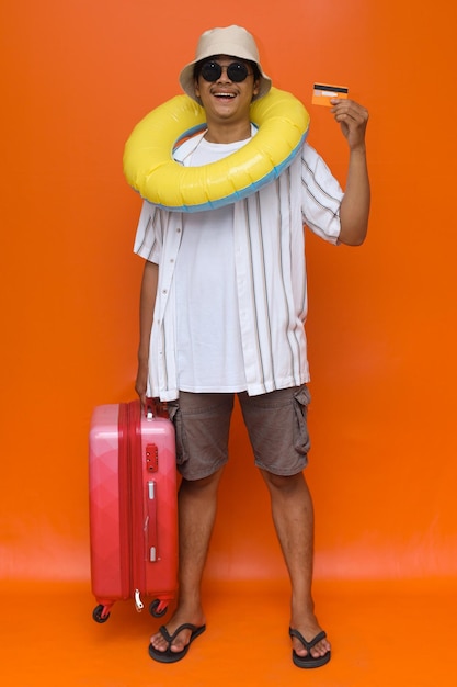 Hombre feliz con maleta yendo de vacaciones de verano. Varón joven sonriente y lleno de alegría que usa ropa casual