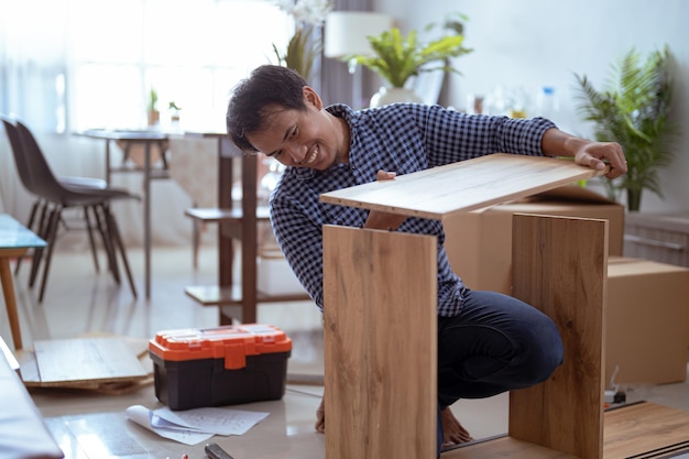 Hombre feliz mientras trabajaba en el montaje de muebles nuevos