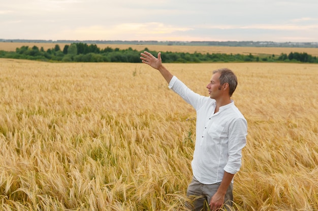 El hombre feliz mira el paisaje del campo de trigo