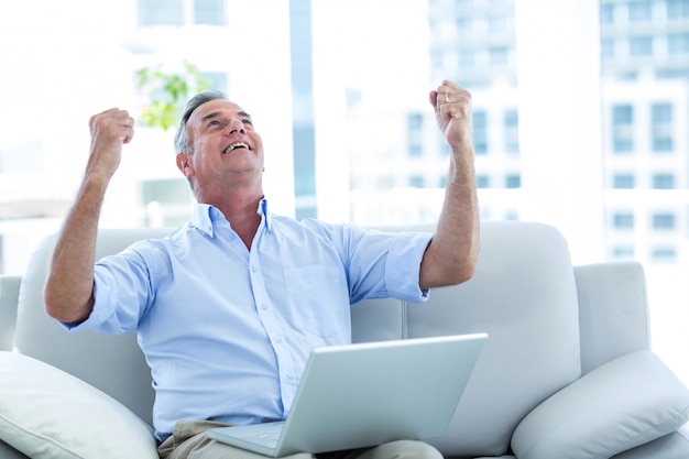 Hombre feliz mirando hacia arriba mientras trabajaba en la computadora portátil