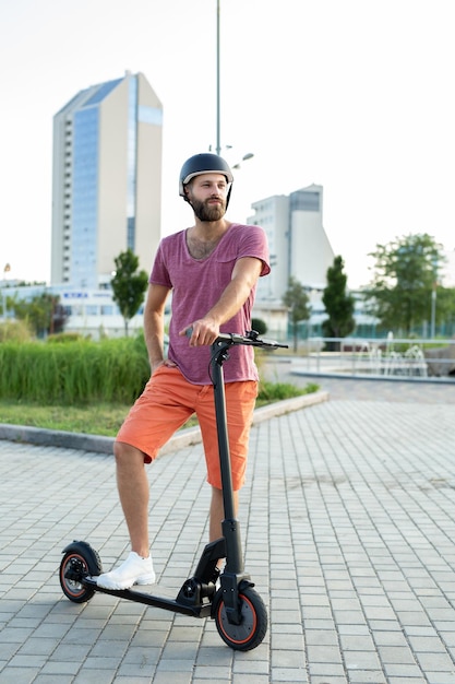 Hombre feliz monta un scooter eléctrico en el parque