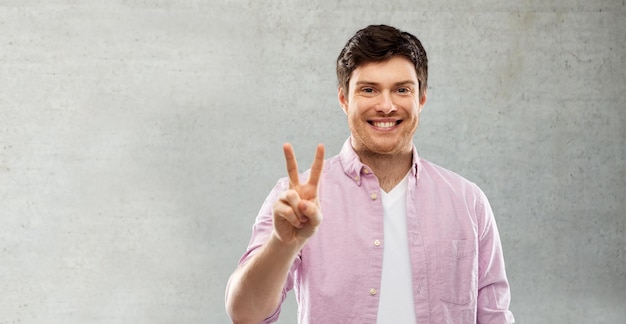 Foto hombre feliz mostrando dos dedos o el signo de la mano de la paz