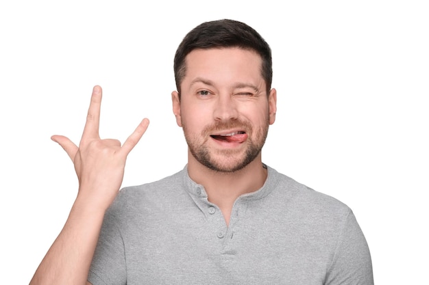 Hombre feliz mostrando su lengua y gesto de roca sobre un fondo blanco