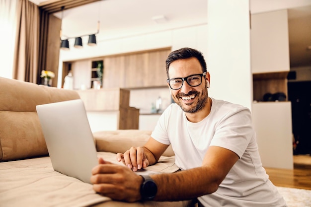 Foto un hombre feliz navegando por internet en casa mientras sonríe a la cámara