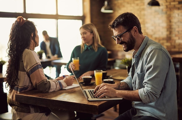 Hombre feliz navegando por la red en la computadora portátil en un café