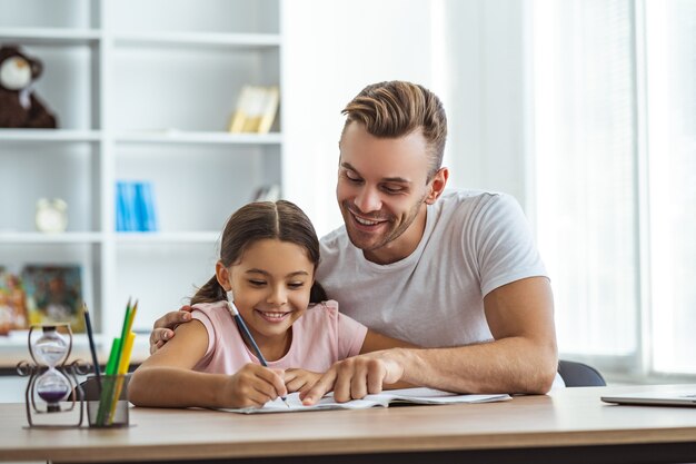 El hombre feliz y una niña haciendo los deberes en el escritorio