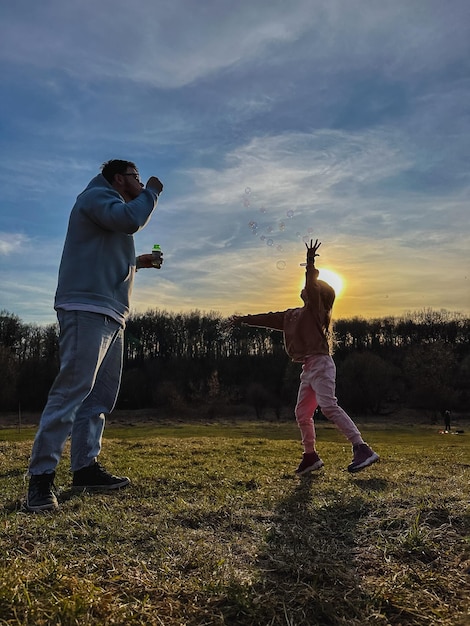 Hombre feliz con una niña jugando con burbujas de jabón