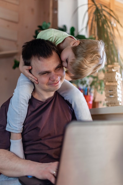 Hombre feliz con niños usando una computadora portátil y auriculares durante su trabajo en casa, la vida en cuarentena