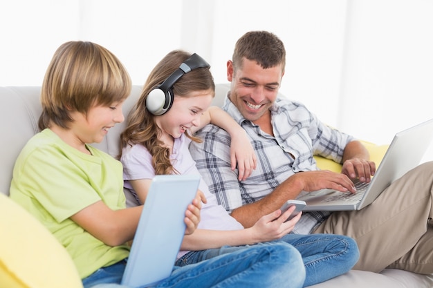 Hombre feliz con niños usando tecnologías