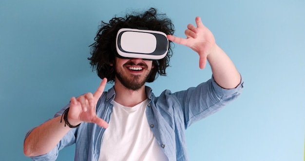 Hombre feliz obteniendo experiencia usando gafas de auriculares VR de realidad virtual, aislado en fondo azul