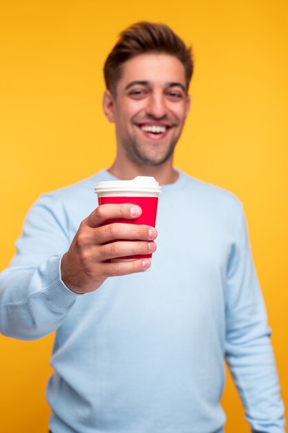 Hombre feliz ofreciendo café a la cámara