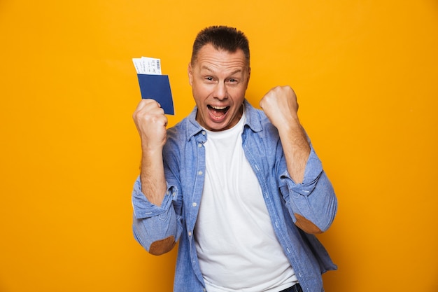 Hombre feliz con pasaporte hace gesto de ganador.