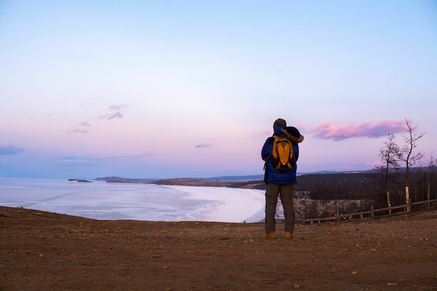 Hombre feliz de pie en el acantilado y mirando la vista del paisaje