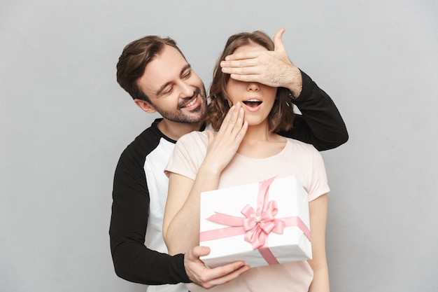 Hombre feliz de pie aislado sosteniendo la caja de regalo actual para su mujer.