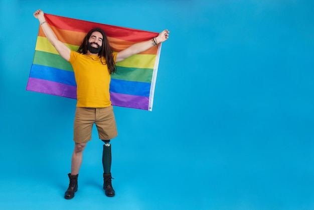 Hombre feliz con una pierna ortopédica ondeando una bandera lgbt