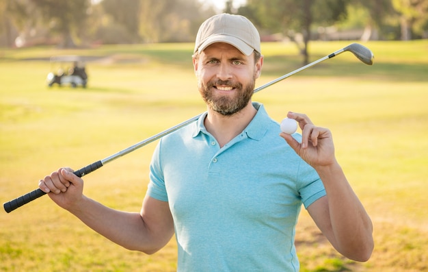 Hombre feliz que muestra la bola del juego de golf en la hierba verde, golf.