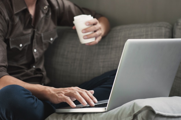 hombre feliz que usa la computadora portátil con café