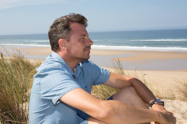 Hombre feliz respirando profundamente en la playa en vacaciones