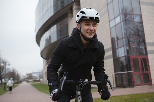 Hombre feliz riendo, disfrutando del ciclismo en la ciudad en otoño o invierno