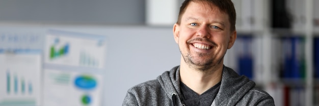 Hombre feliz en ropa casual está de pie y sonriendo. El hombre durante la cuarentena organizó el lugar de trabajo en un apartamento. Respire antes de la nueva semana laboral. Planes de desarrollo estratégico empresarial en acceso remoto