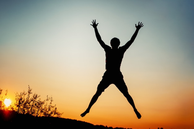 Foto hombre feliz saltando de alegría al atardecer. concepto de éxito y felicidad.